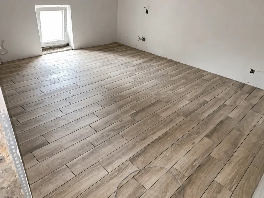 Pose de carrelage imitation bois dans une pièce en rénovation